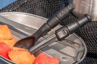 9909MIL: Black spork being used to cut into canned fruits on tin surface.